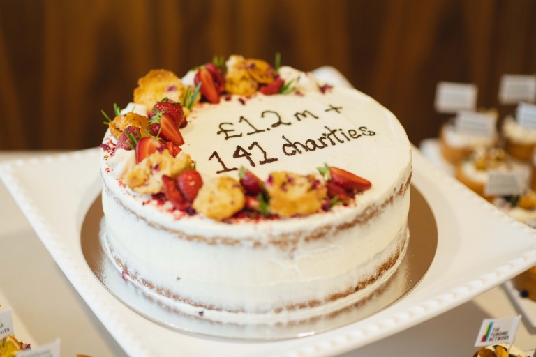 Cake with '£1.2m + 141 Charities' decorated in writing