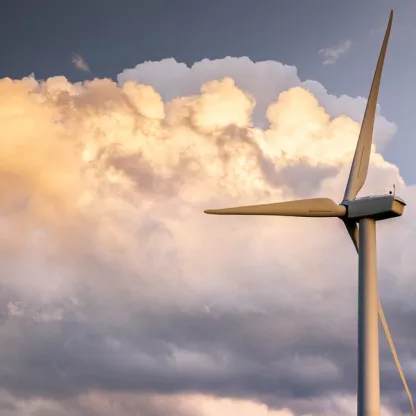 Wind turbine with sunlit clouds in background