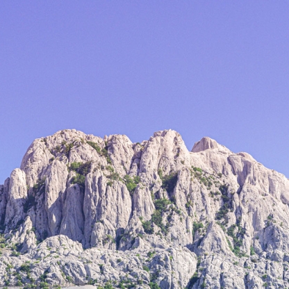 Light grey mountain landscape below a clear lilac sky